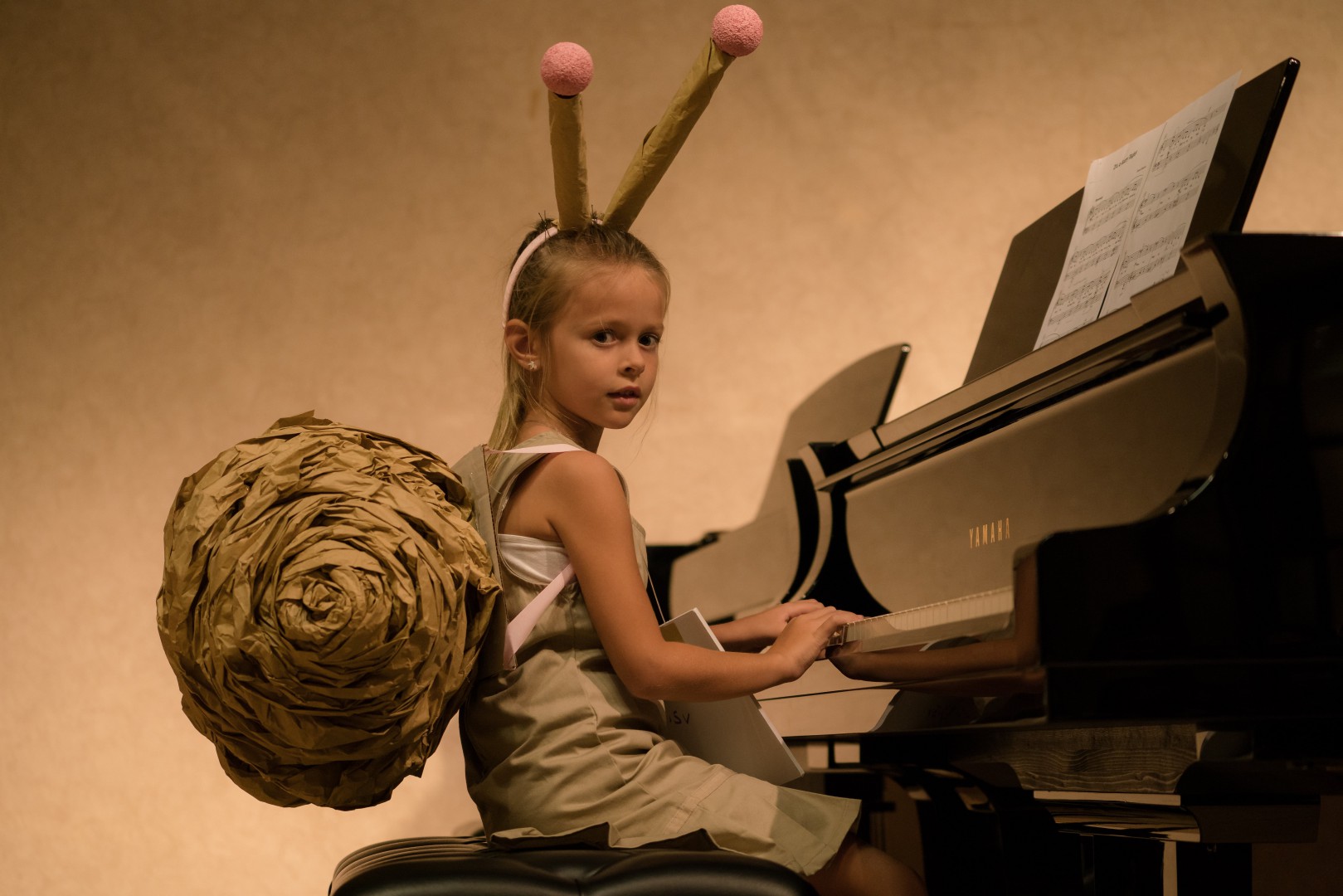 Little girl in a snail costume playing the piano