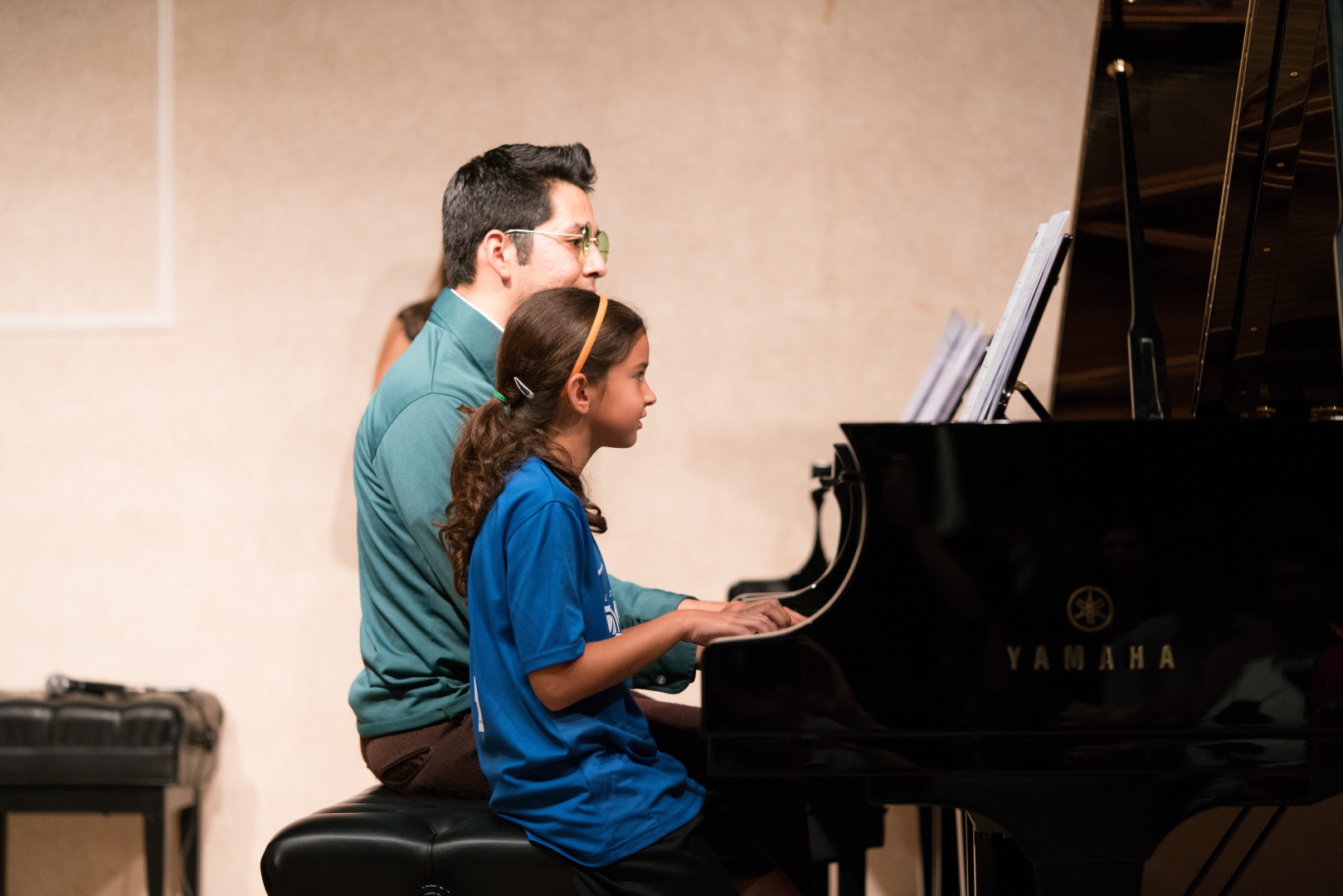 Little girl with her instructor playing the piano
