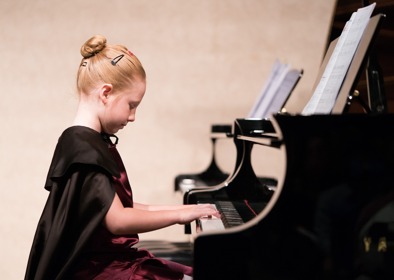 Little girl in a cape costume playing the piano