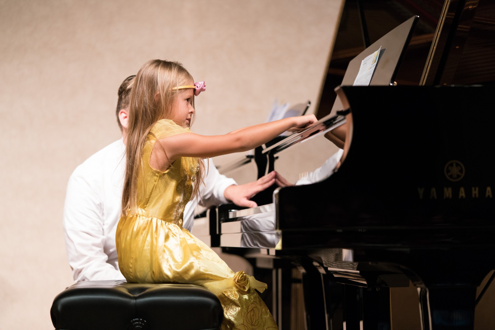 Little girl in a yellow fairy dress playing the piano