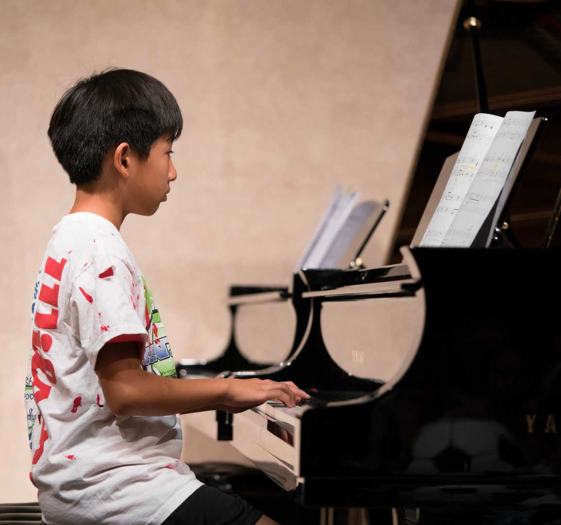 Little boy in a casual dress playing the piano