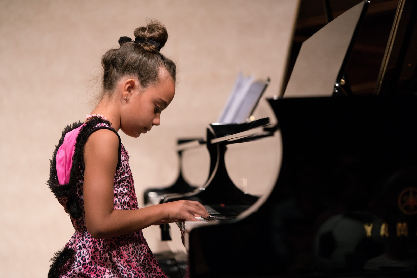Little girl in pink and dress costume playing the piano