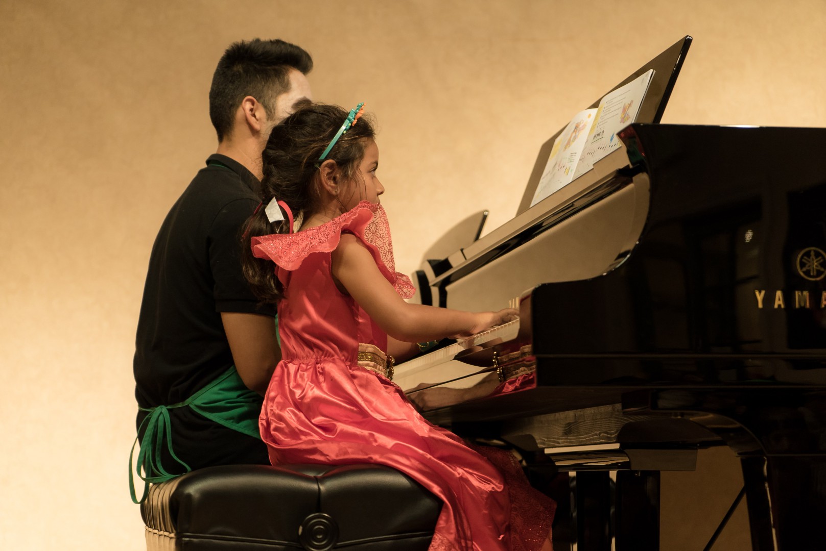 A young man and a little girl playing the piano