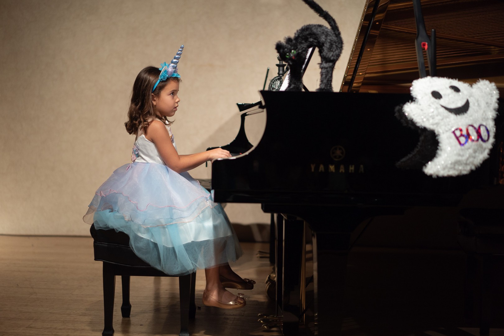 Little girl in blue and white fairy dress playing the piano